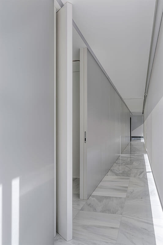 Puerta pivotante oculta abierta en pasillo